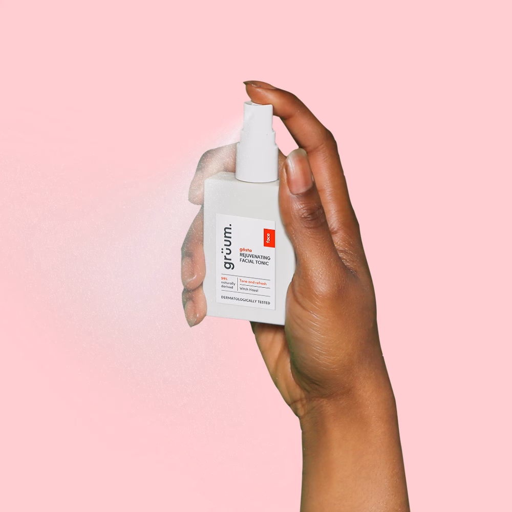 Hand holding facial tonic spray bottle.