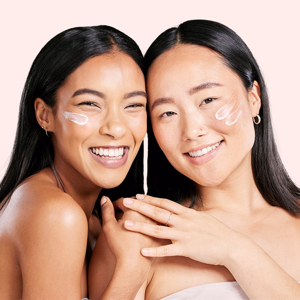 Two women with face cream smiling.