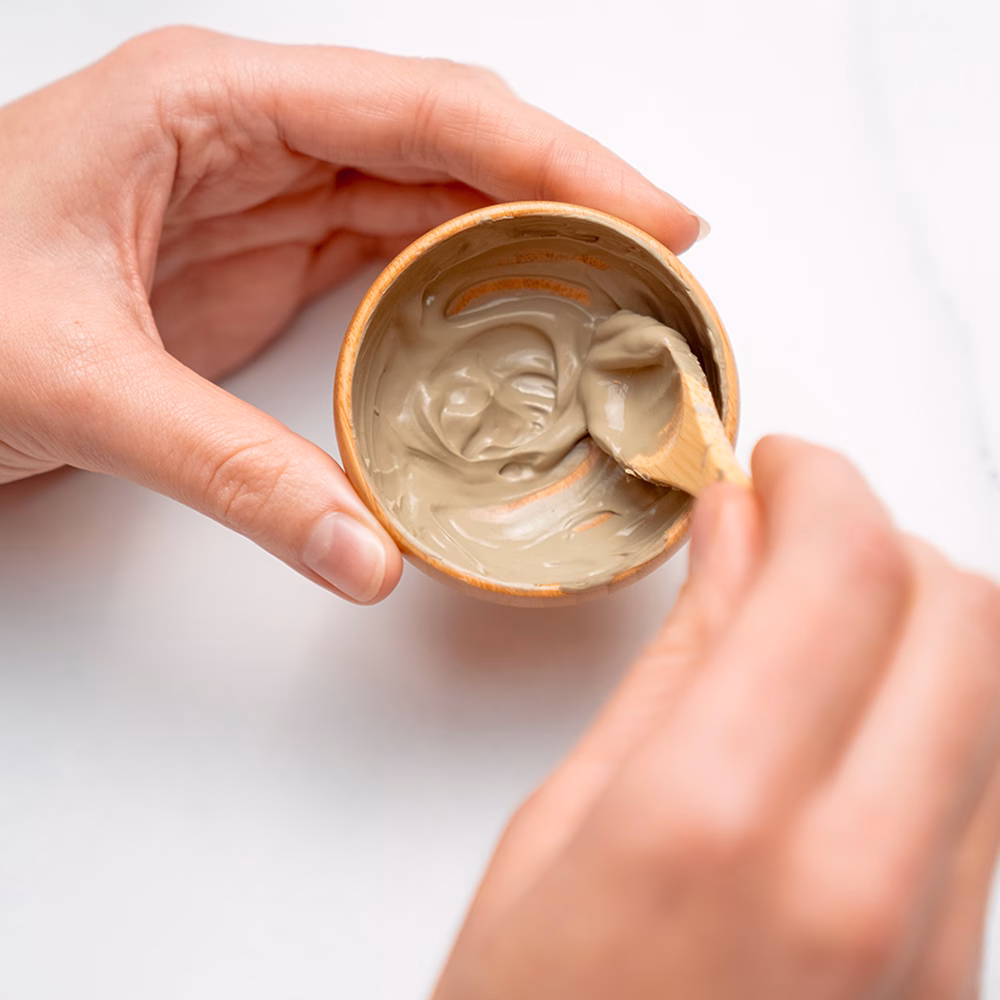 Hands mixing clay mask in bowl