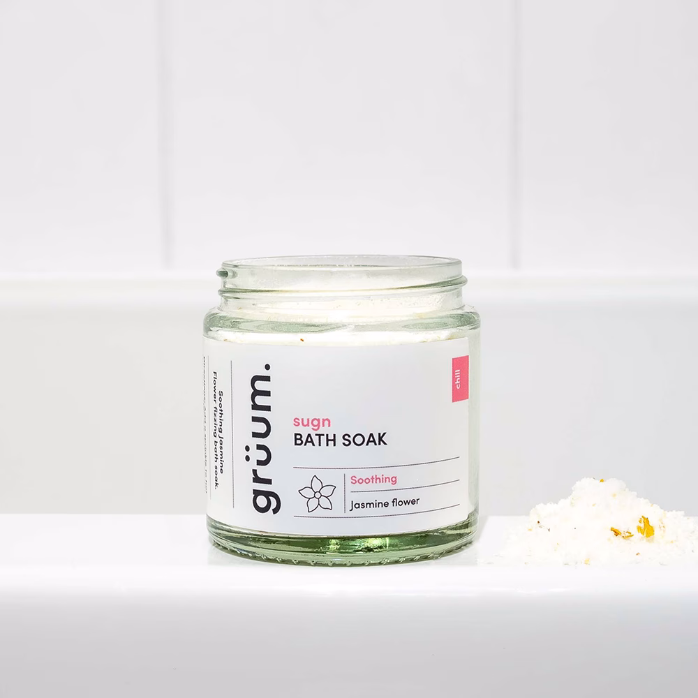 Glass jar of bath soak on tub.