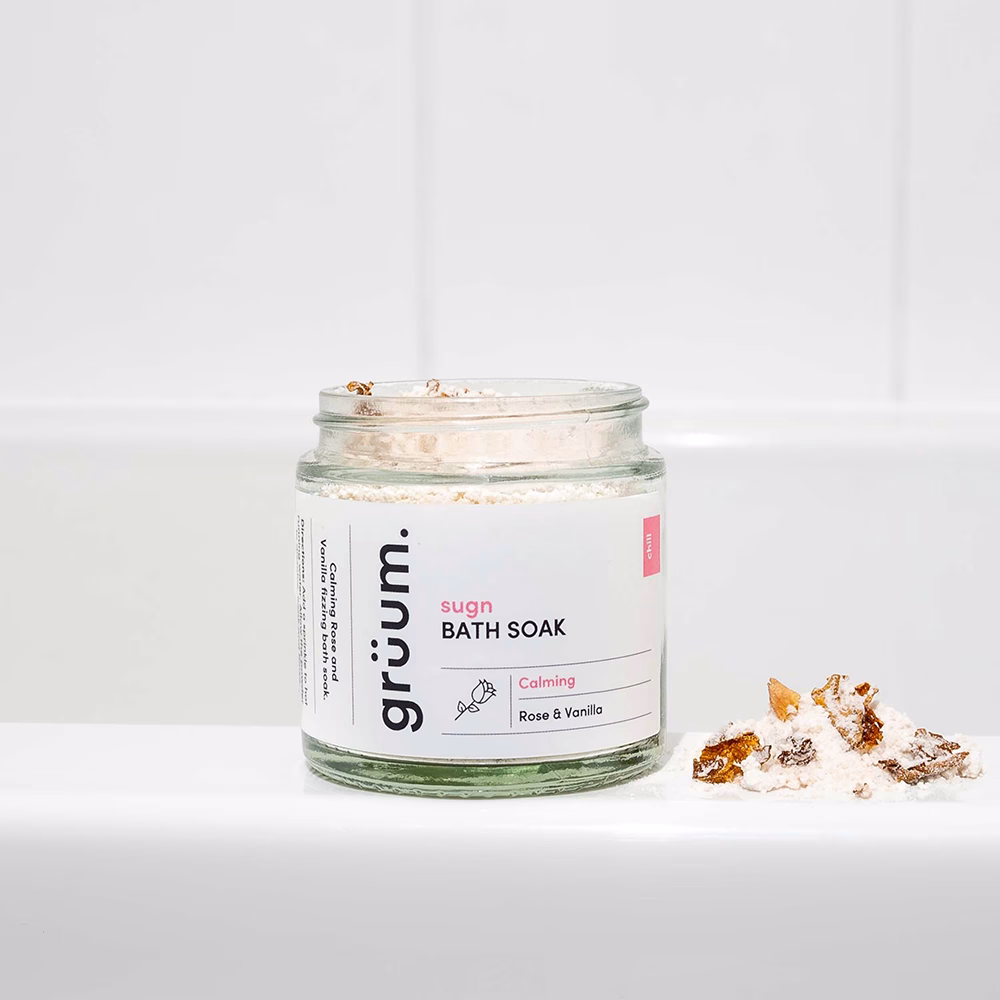 Jar of bath soak on bathtub edge.