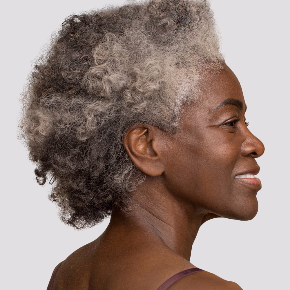 Smiling woman with curly gray hair.