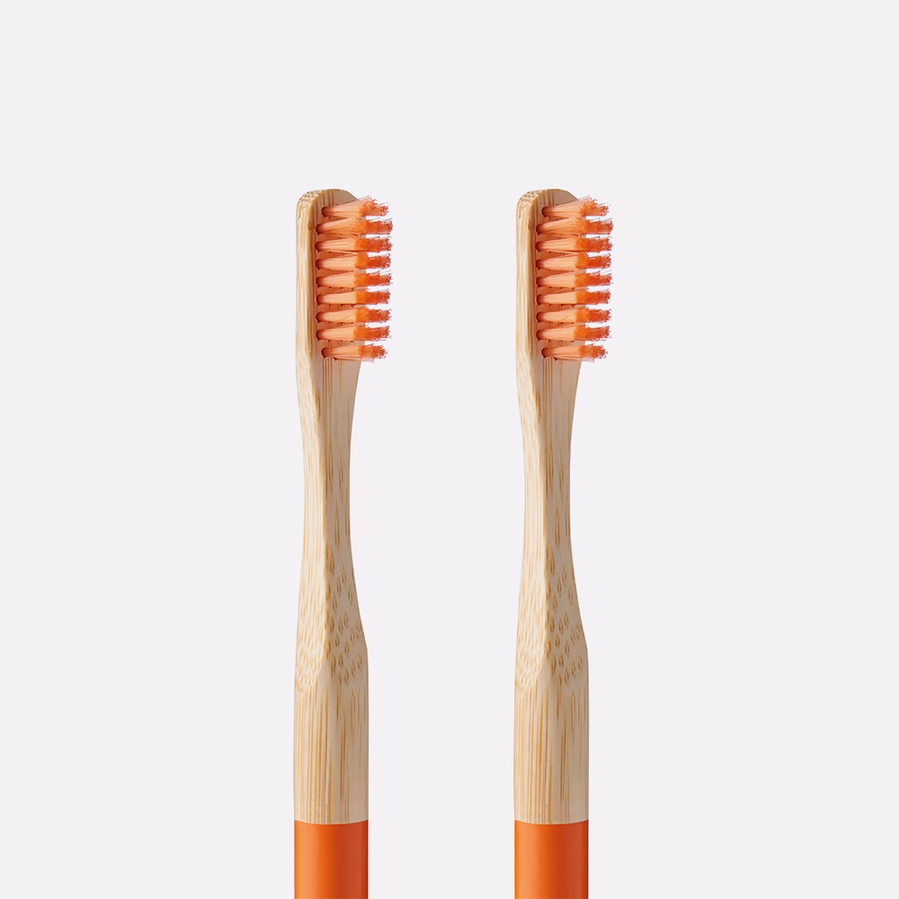Two bamboo toothbrushes with orange bristles