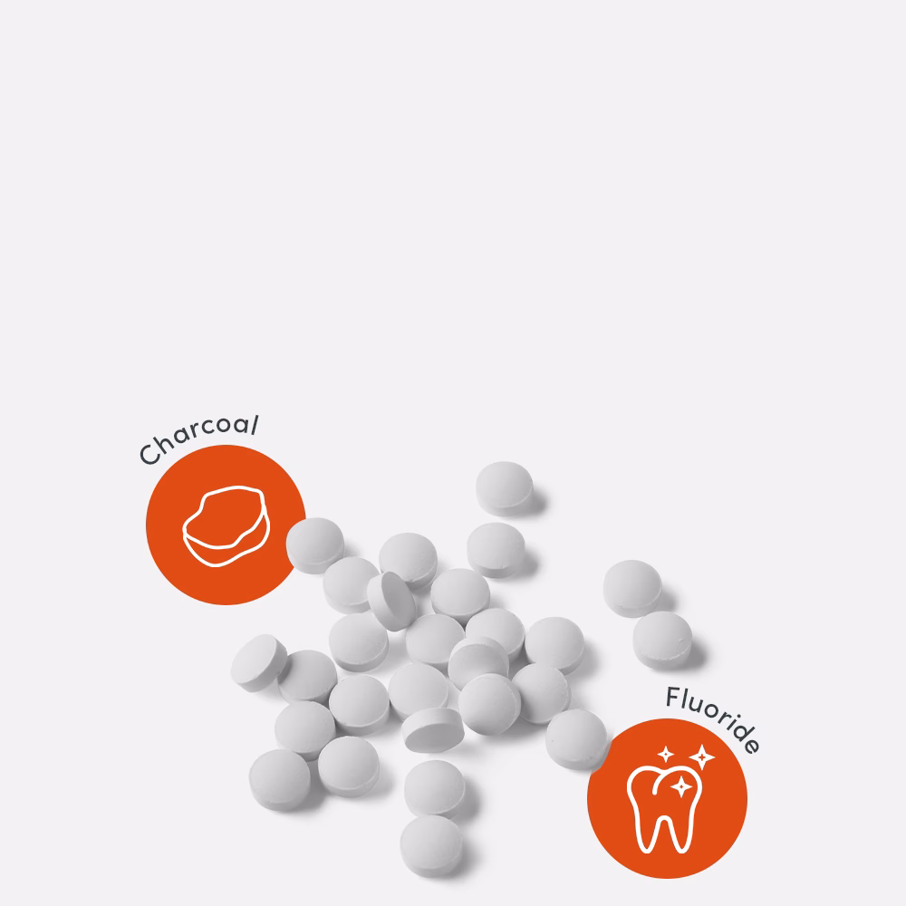 White tablets with charcoal and fluoride icons.