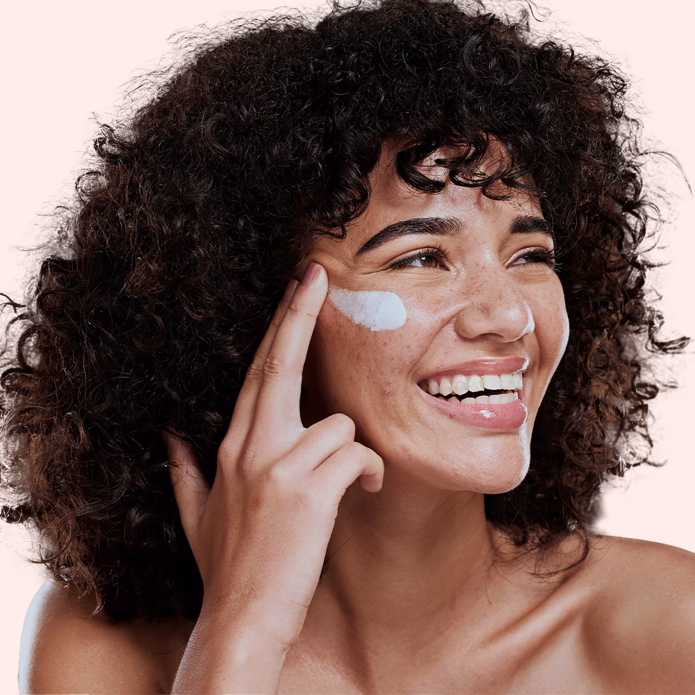 Woman applying face cream, smiling