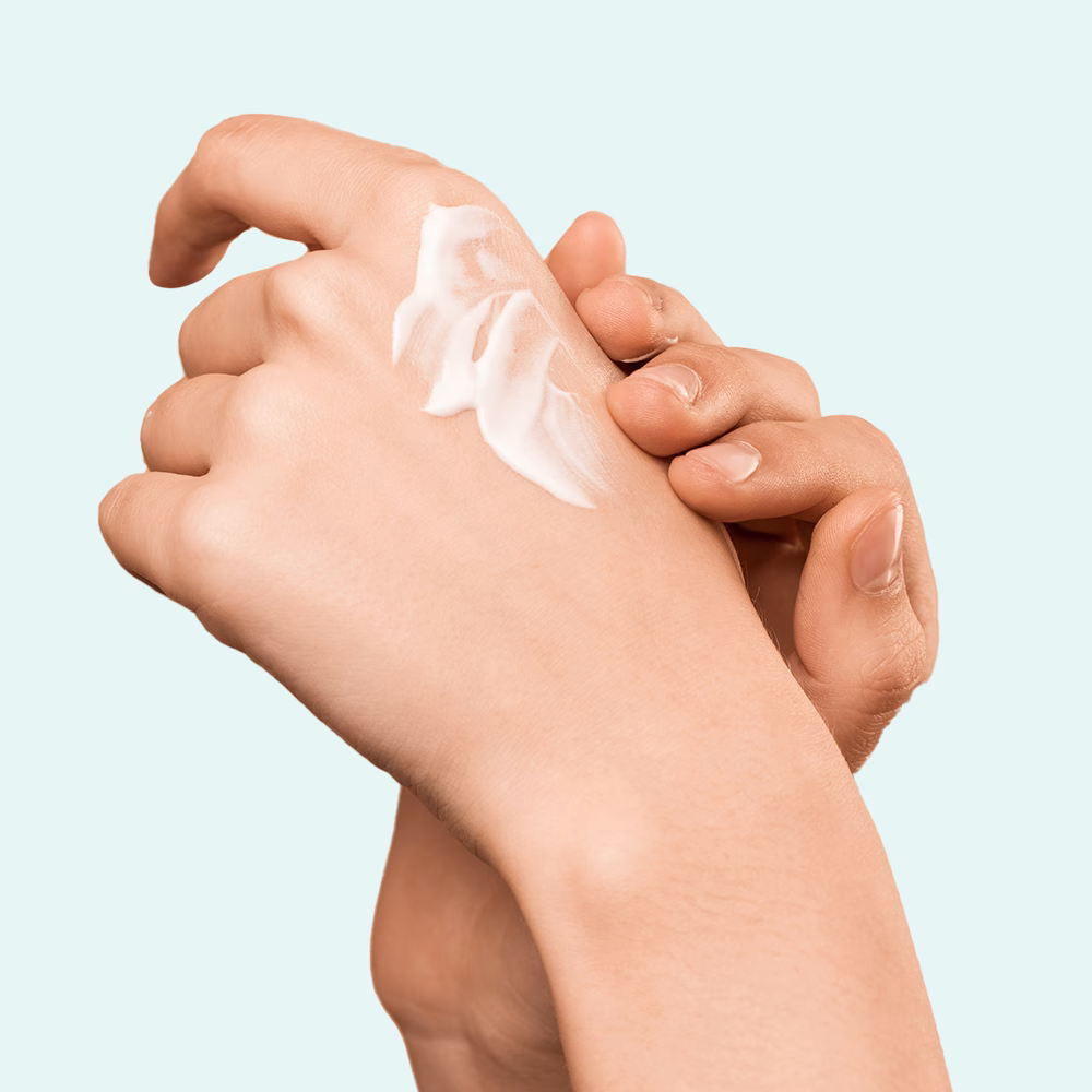 Hands applying lotion on skin