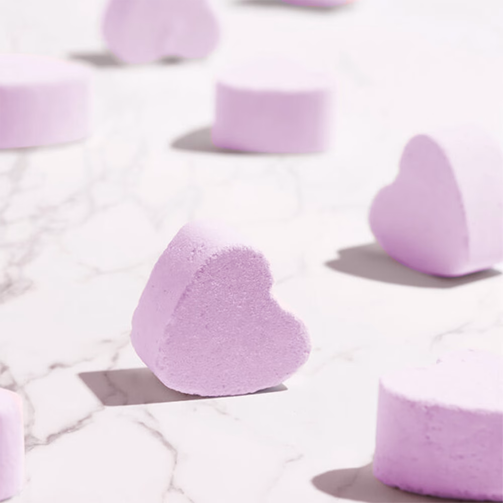 Purple heart-shaped bath bombs on marble