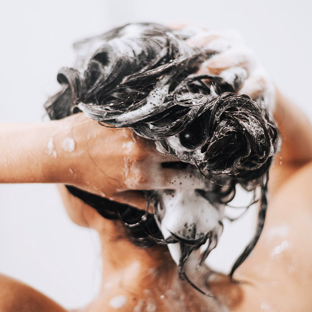 Person washing hair with soap suds
