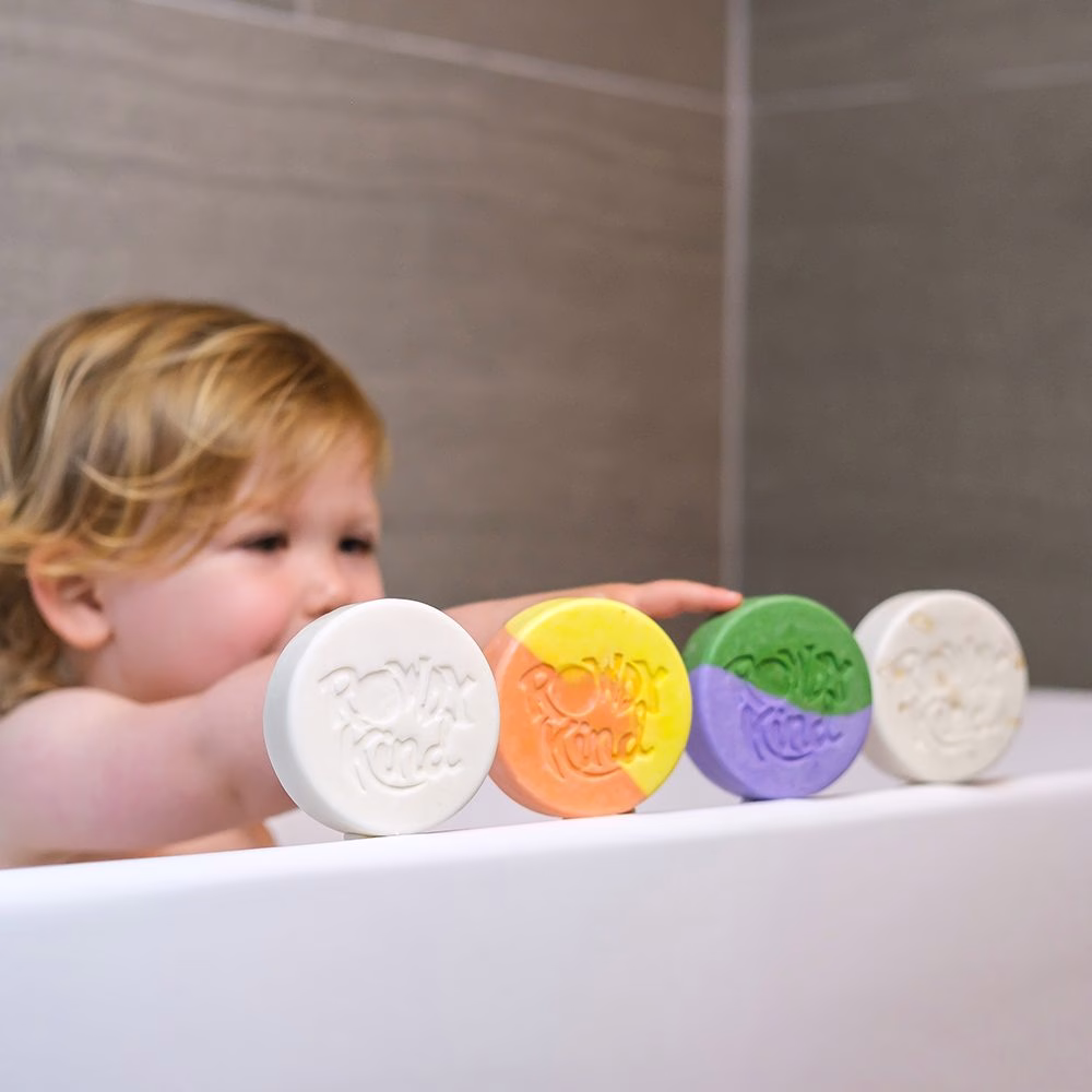 Child in bathtub with colorful soaps