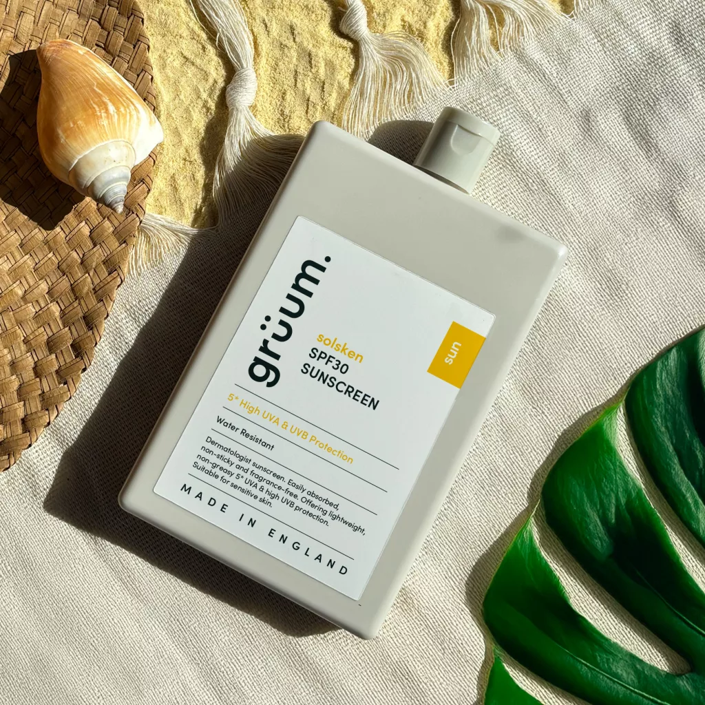 Sunscreen bottle on fabric with shell and leaf.