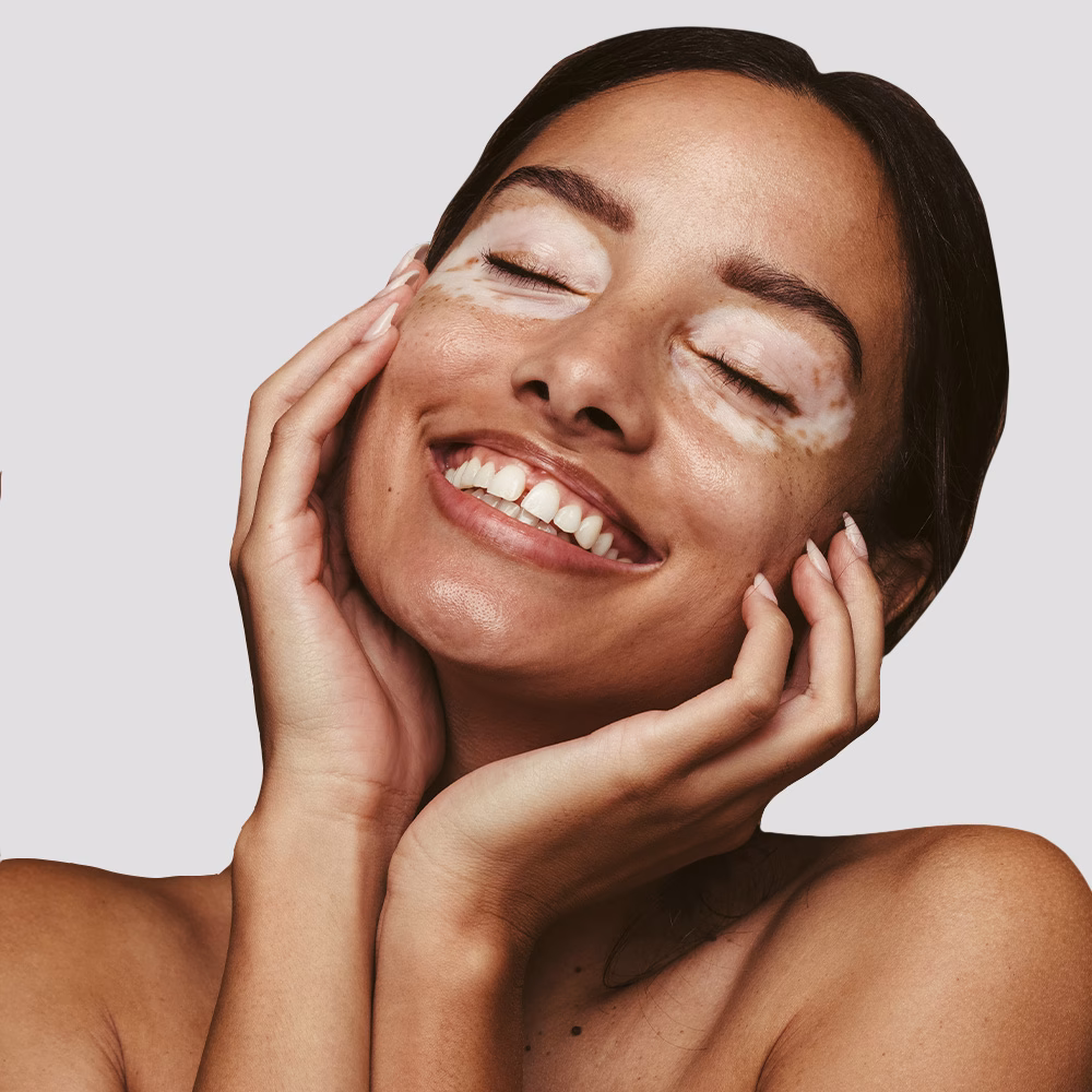 Smiling woman with eyes closed, touching face.