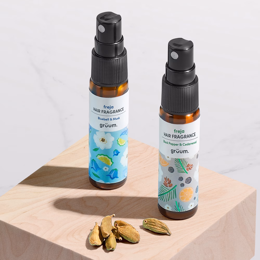 Two hair fragrance bottles on wood block.