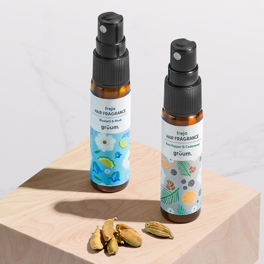 Two hair fragrance bottles on wood block.