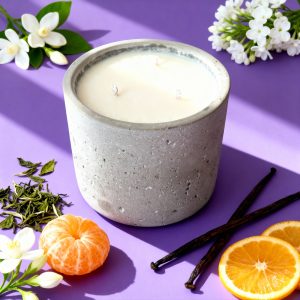 Candle with citrus and flowers on purple background.