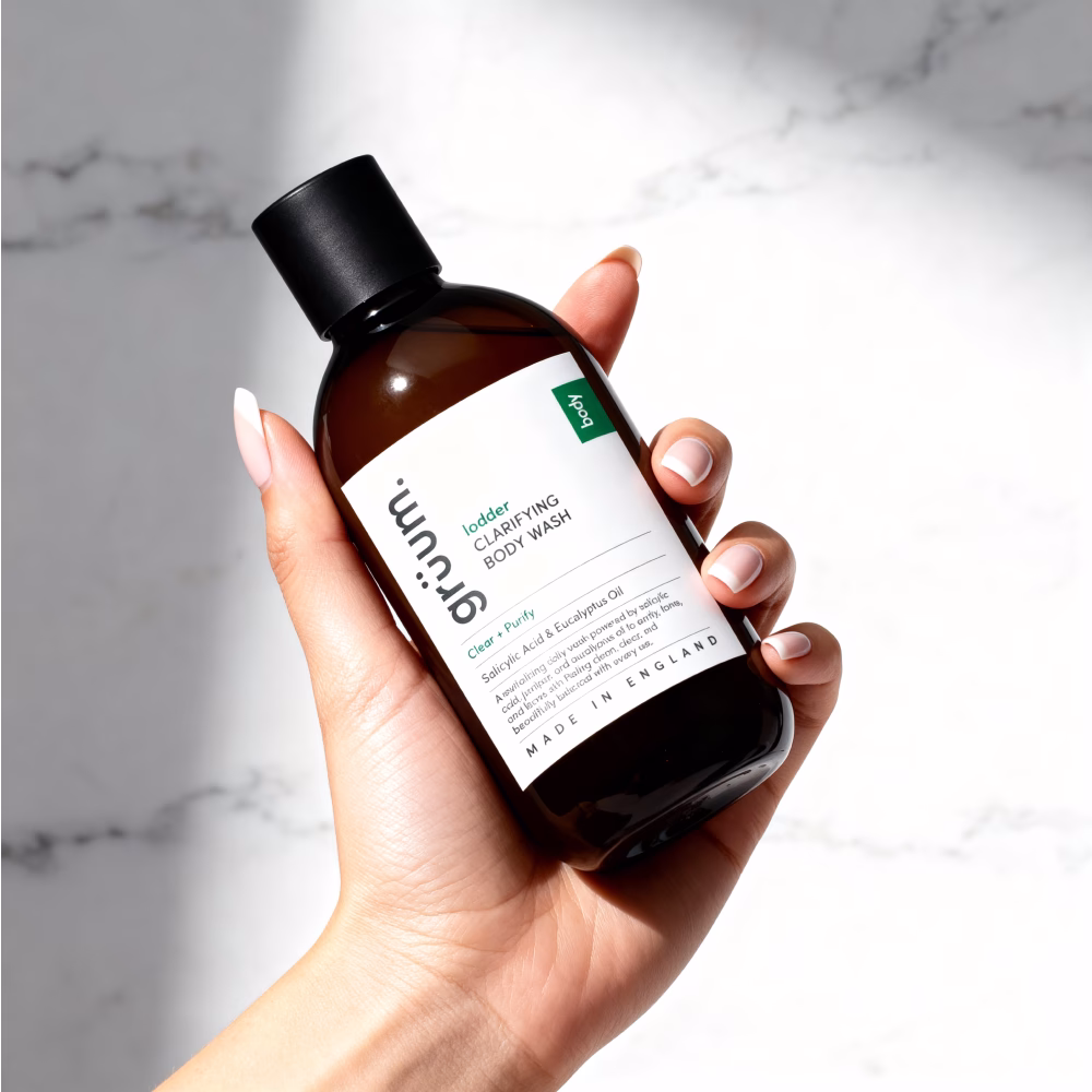 Hand holding clarifying body wash bottle.