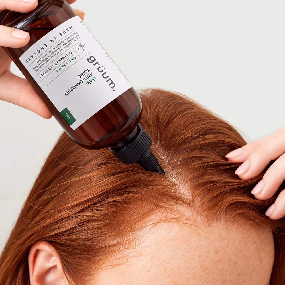 Bottle applying scalp tonic to parted red hair